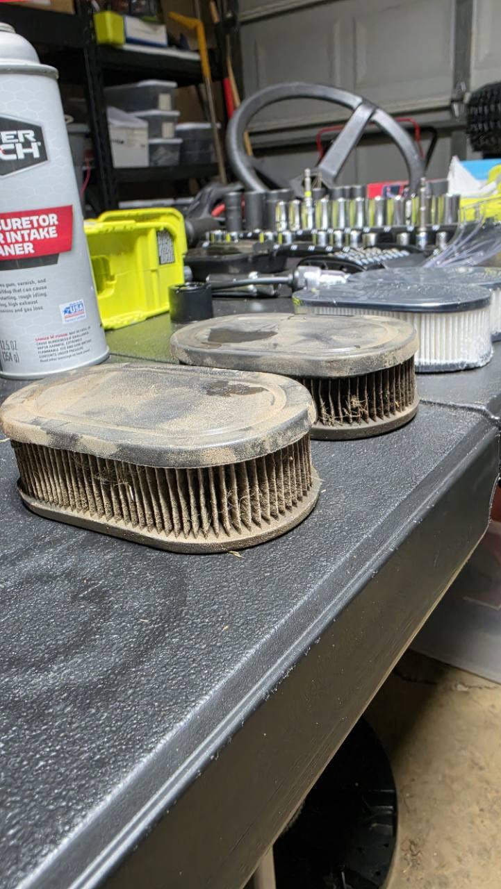 Three used small engine air filters on a workbench
